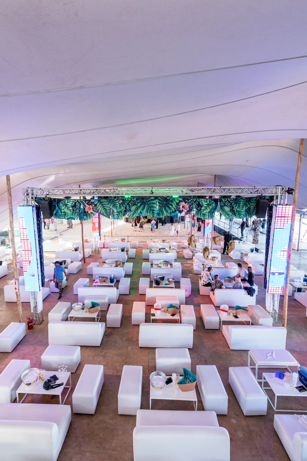Rows of white VIP tables under the beach stage tent